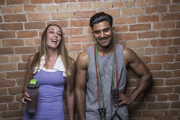 Smiling man and woman against brick wall in gym