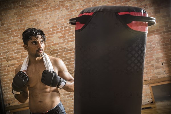 Shirtless man with boxing gloves and towel in gym