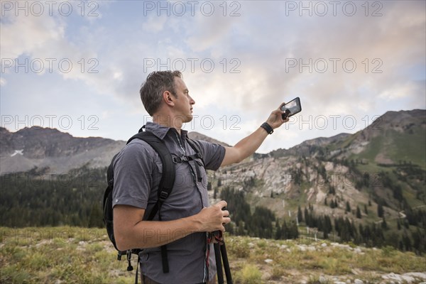 Male hiker photographing mountain landscape