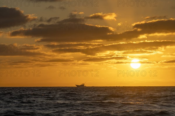 Small fishing boat in ocean at sunrise