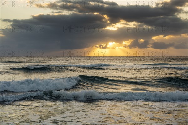 Ocean and dramatic golden streaks from morning clouds