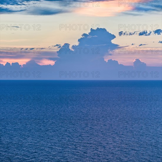 Ocean and dramatic cumulus clouds with blue sunrise sky