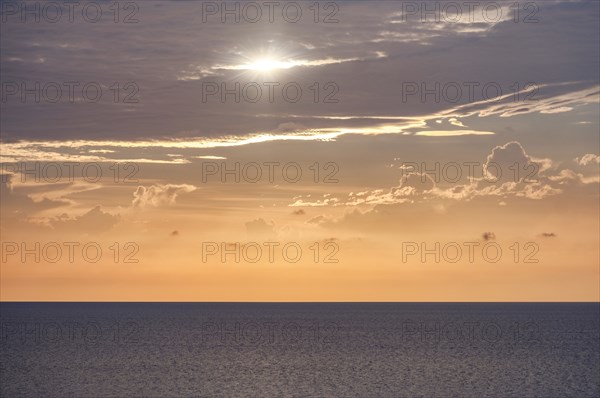 Sun shining through clouds above ocean