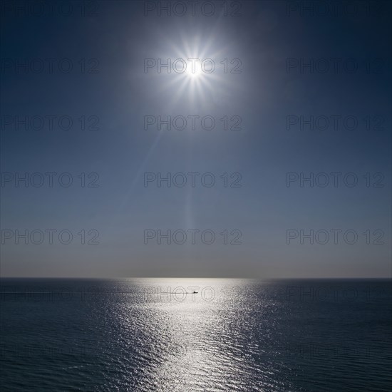 Sun shining above calm ocean surface