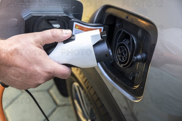 Mans hand holding charge cable in electric vehicle