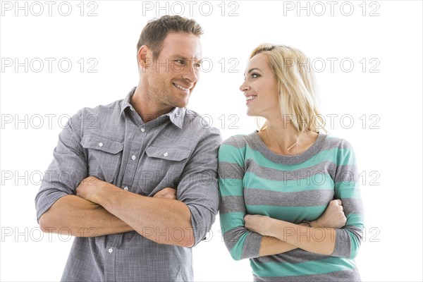 Studio shot of smiling couple with arms crossed