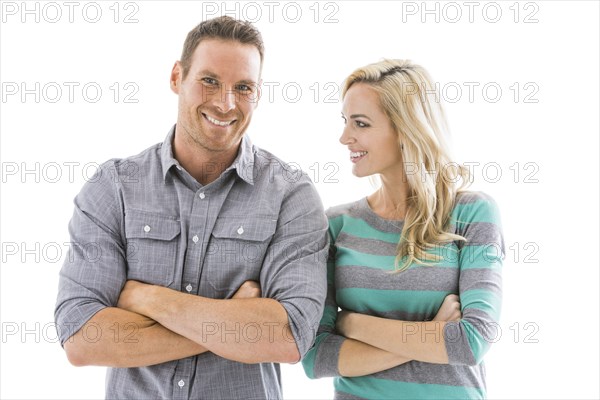 Studio shot of smiling couple with arms crossed