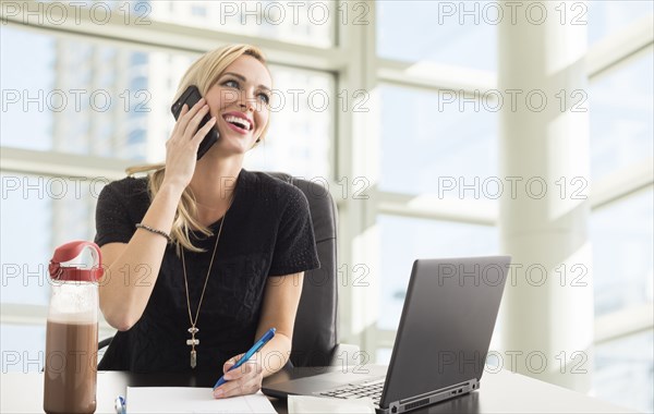 Smiling businesswoman talking on phone in office