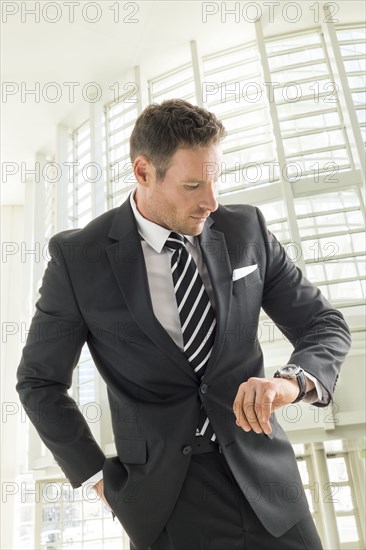 Businessman looking at wristwatch in office