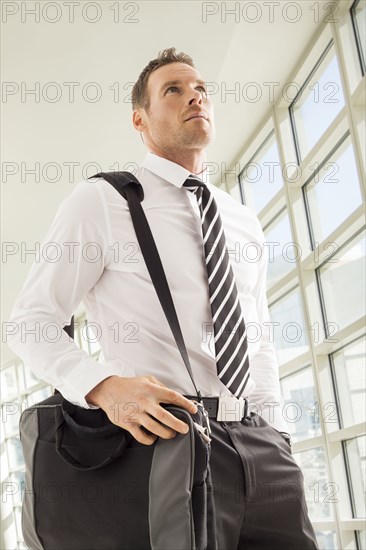 Low angle view of businessman with shoulder bag in office