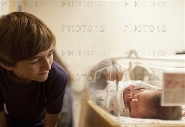 Boy (12-13) looking at newborn baby sister (0-1 months) in incubator