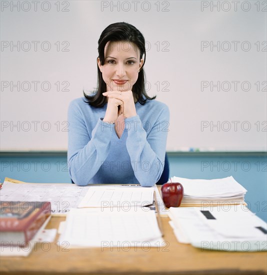 Portrait of teacher sitting behind desk