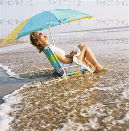 Woman sitting in chair under umbrella