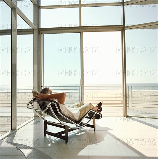 Man lying on reclining chair in house