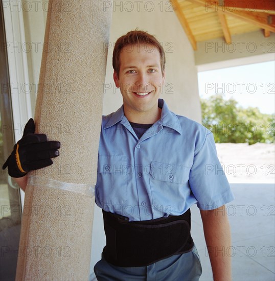 Portrait of man holding rolled rug