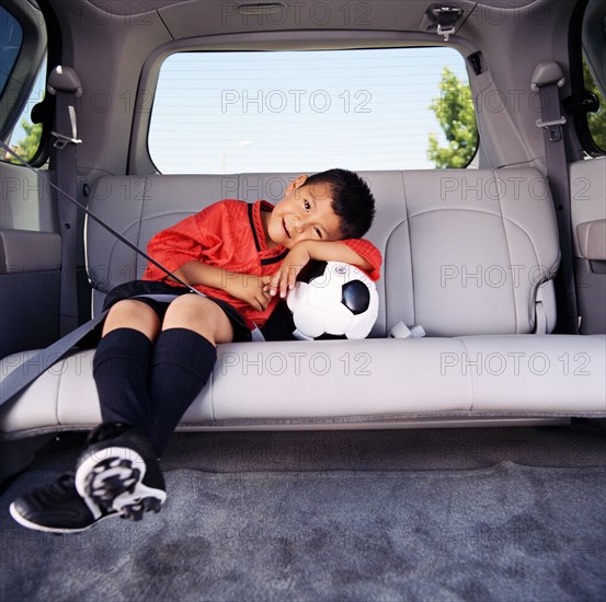 Portrait of boy (4-5) in soccer uniform sitting in car