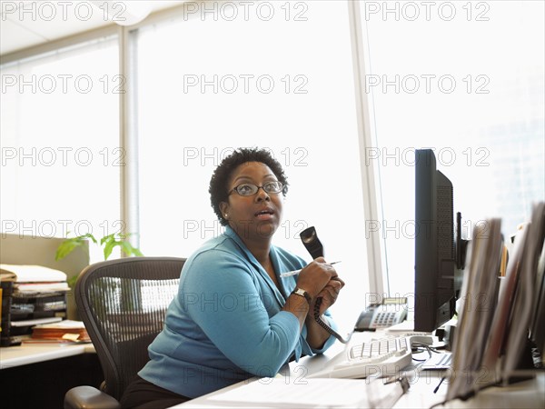 Businesswoman sitting at desk with telephone