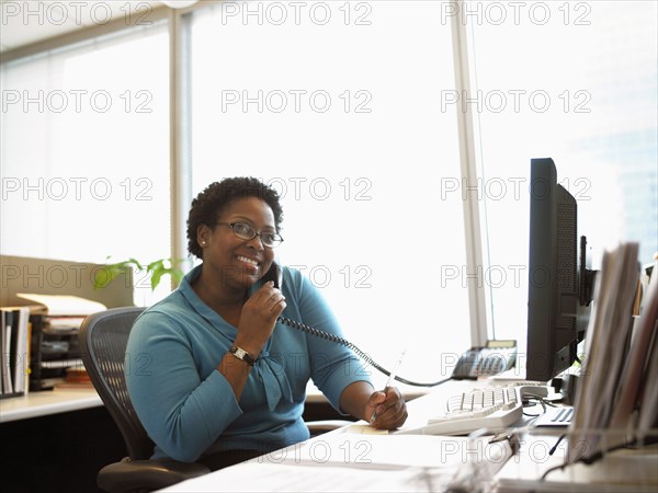 Businesswoman sitting at desk using telephone