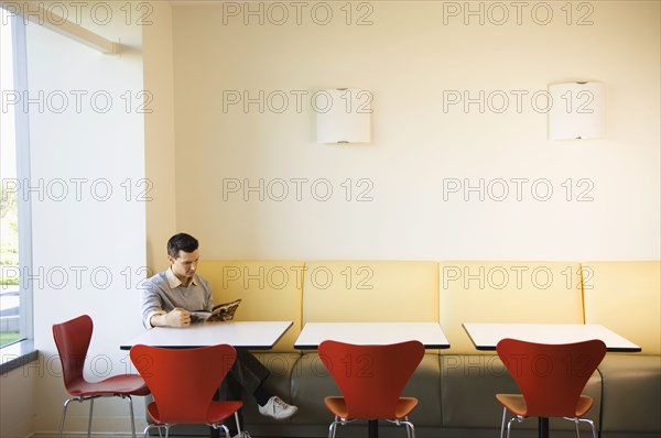 Businessman reading magazine in cafeteria