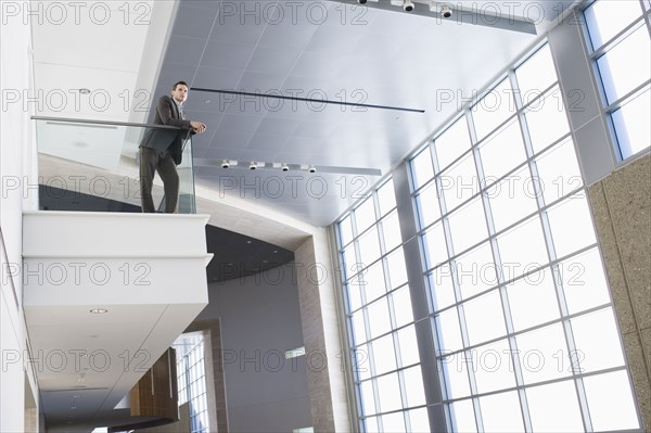 Businessman leaning on balcony in building lobby