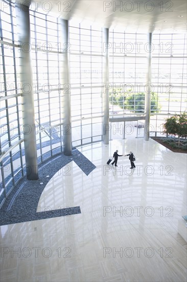 Business people shaking hands in modern lobby