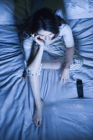 Woman sitting on bed using mobile phone