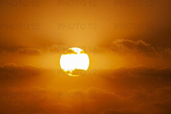 Sun with orange clouds in sunset sky