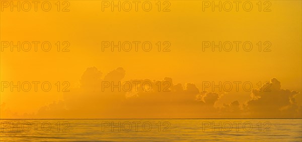 Golden sunrise clouds over calm ocean