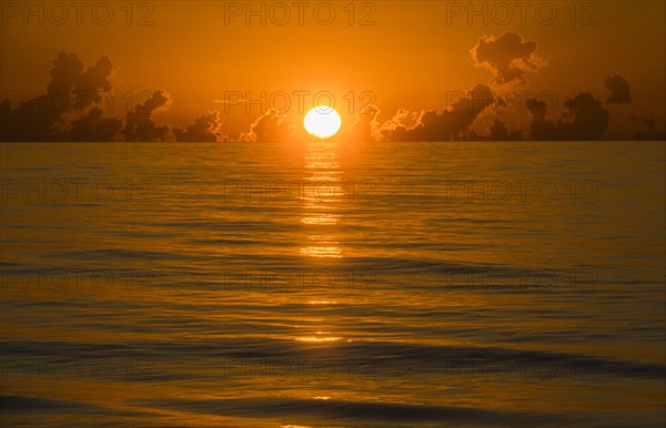 Sun rising above calm ocean