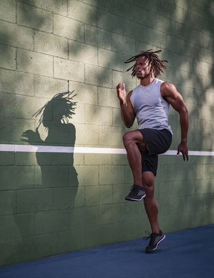 Athletic man jumping next to wall