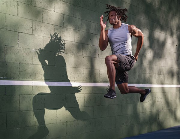 Athletic man jumping next to wall