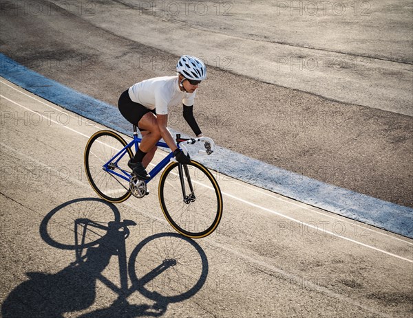 Athletic woman with amputated hand cycling on track