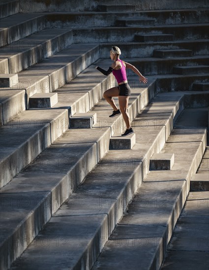 Athletic woman with amputated hand running up steps