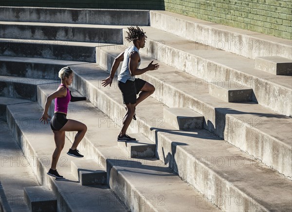 Athletic man and woman with amputated hand running up steps