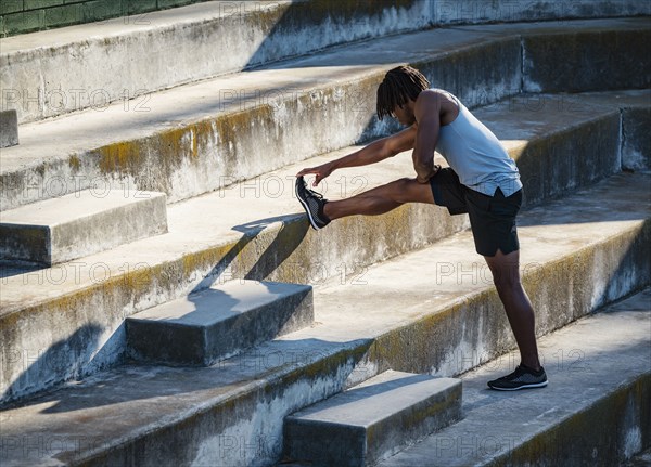 Athletic man stretching leg on steps