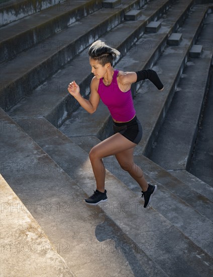 Athletic woman with amputated hand running up steps