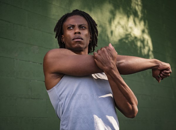 Athletic man stretching arm outdoors