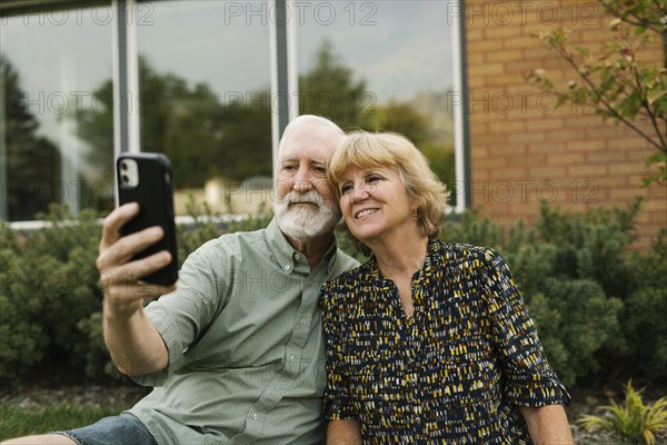 Smiling senior couple taking selfie in backyard
