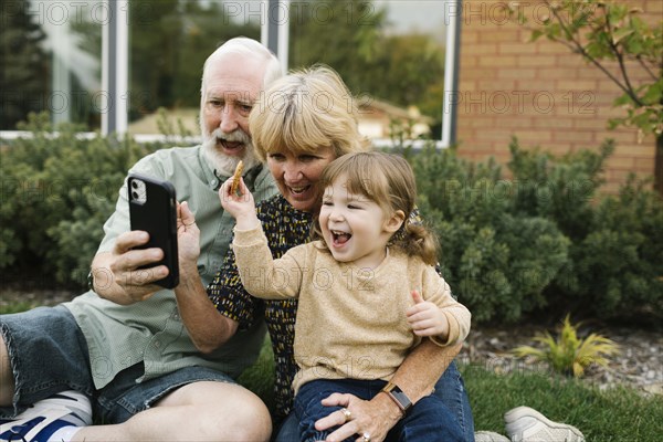 Smiling grandparents taking selfie with granddaughter