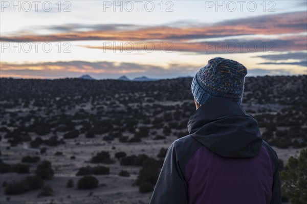 Rear view of woman in desert landscape at sunset