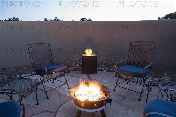 Chairs around back yard fire pit at dusk