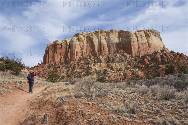 Rear view of female hiker photographing mesa in desert landscape