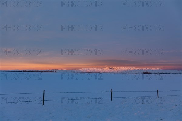 USA, Idaho, Bellevue, Snow covered field with hills in distance at sunrise