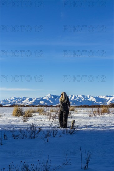 Senior blonde woman snow shoeing in snow covered landscape