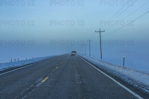 Car heading into fogbank along Highway 20 in winter