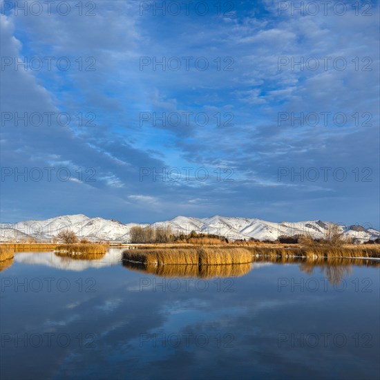 Calm river with snow covered hills in background