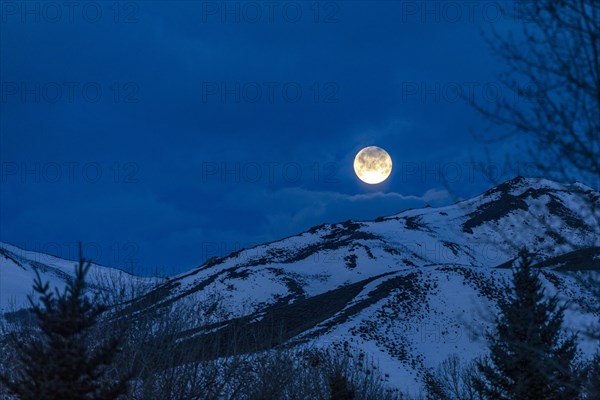 Full moon over snow covered hills at night