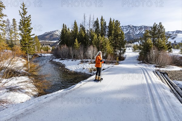 Senior blonde woman snowshoeing in snow covered landscape