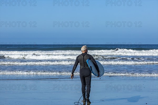 Senior surfer carrying surfboard