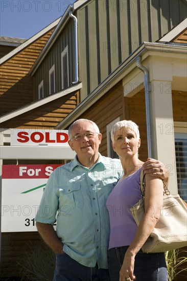 Happy couple in front of new house